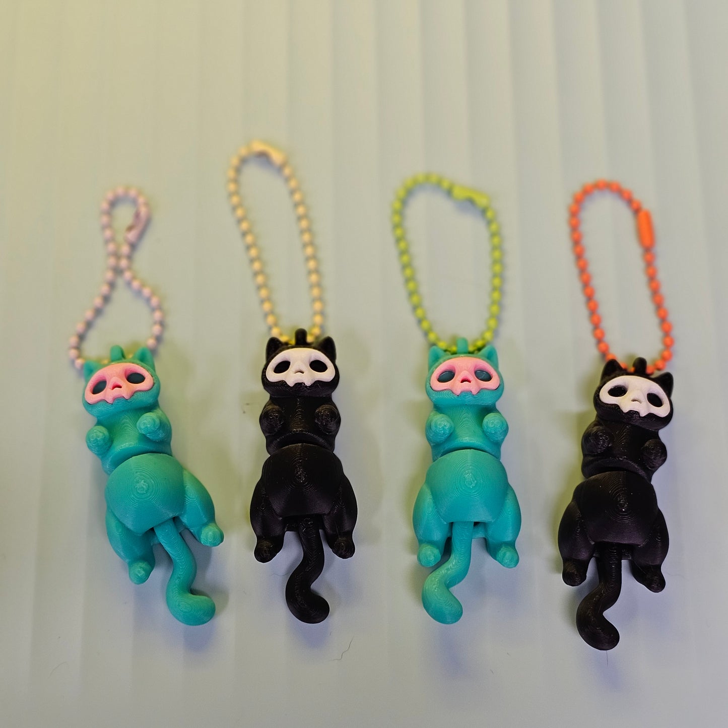 Three colorful keychains with cartoon-like figures on a light gray background