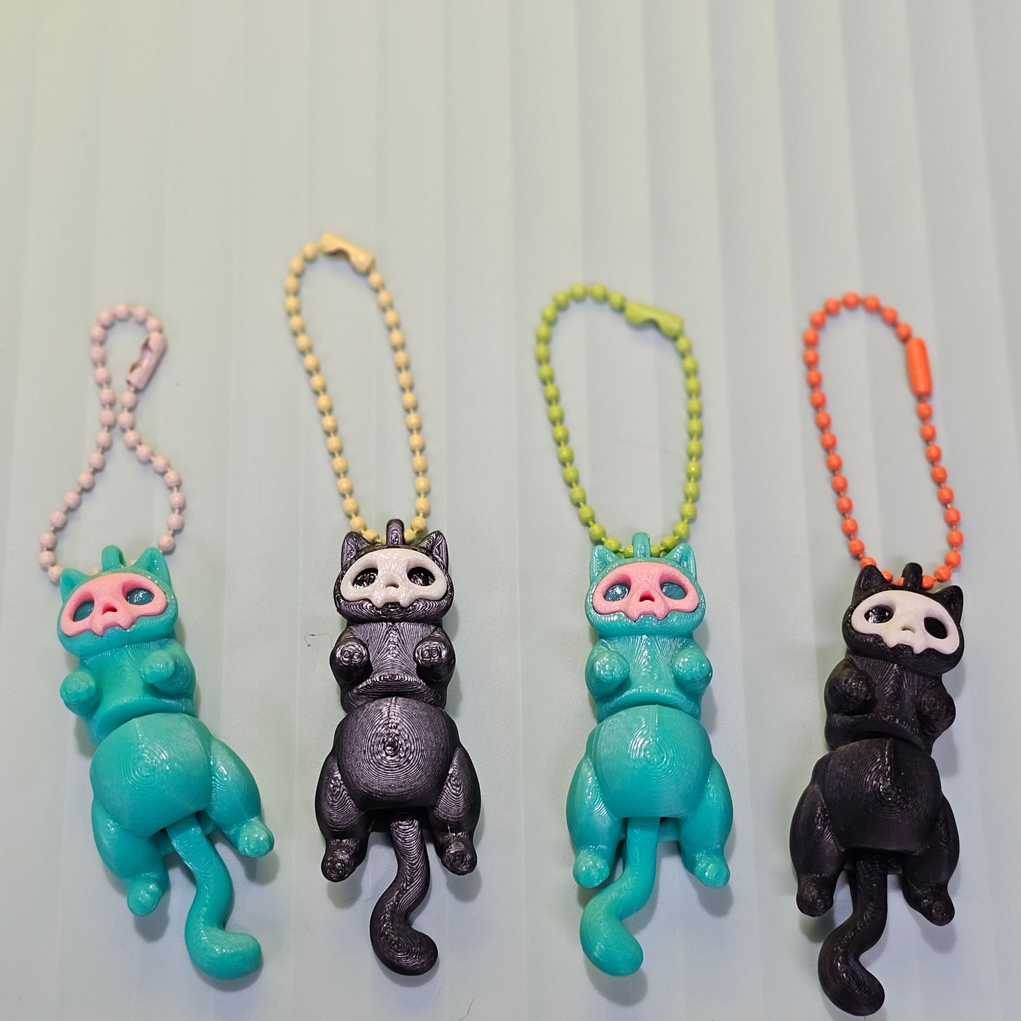 Set of four cat-shaped keychains on a light gray background