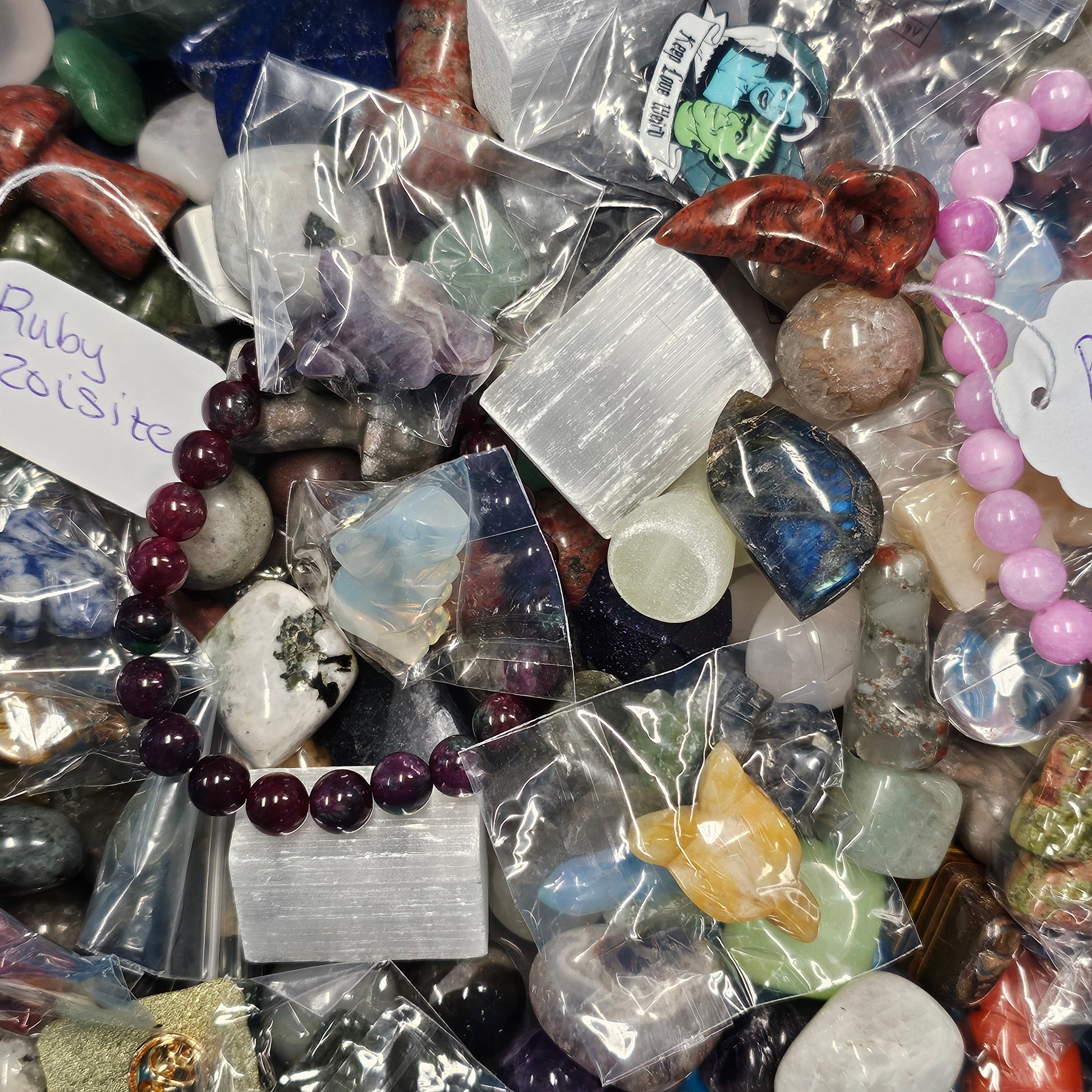 Assorted gemstones and crystals in clear bags with labels.
