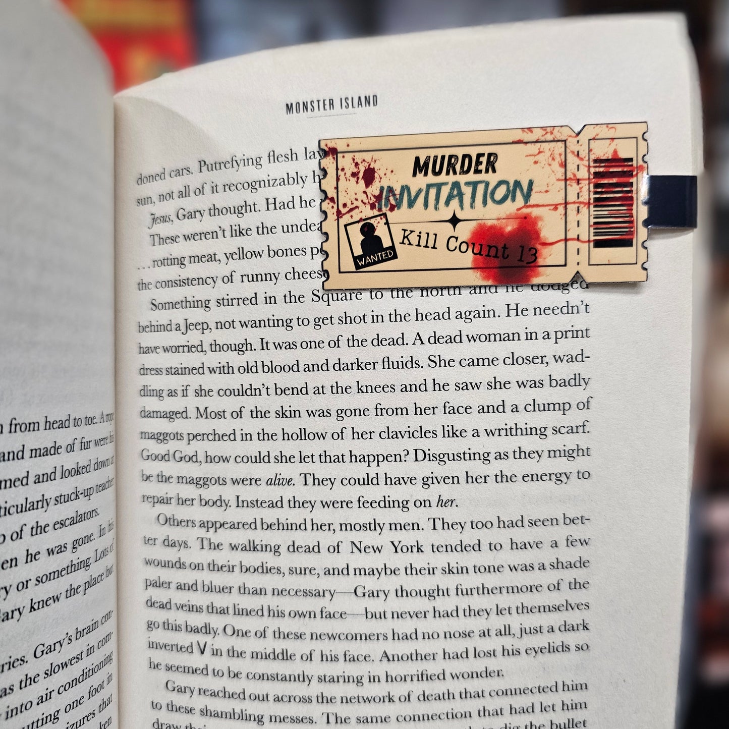 Book with a 'Murder Invitation' bookmark featuring bloodstains on a blurred background