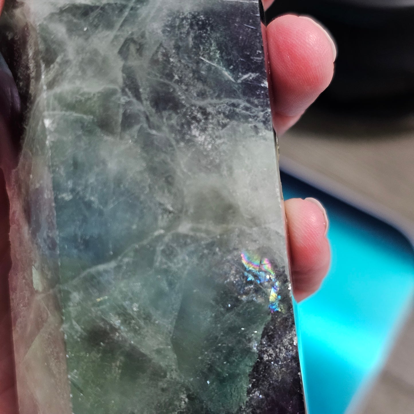 Close-up of a hand holding a rough-cut gemstone with visible texture and color variations.