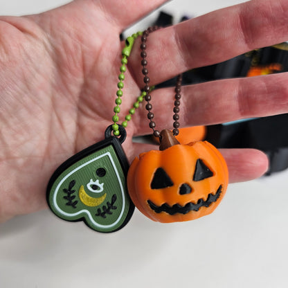 Showing pumpkin and planchette clicker keychains