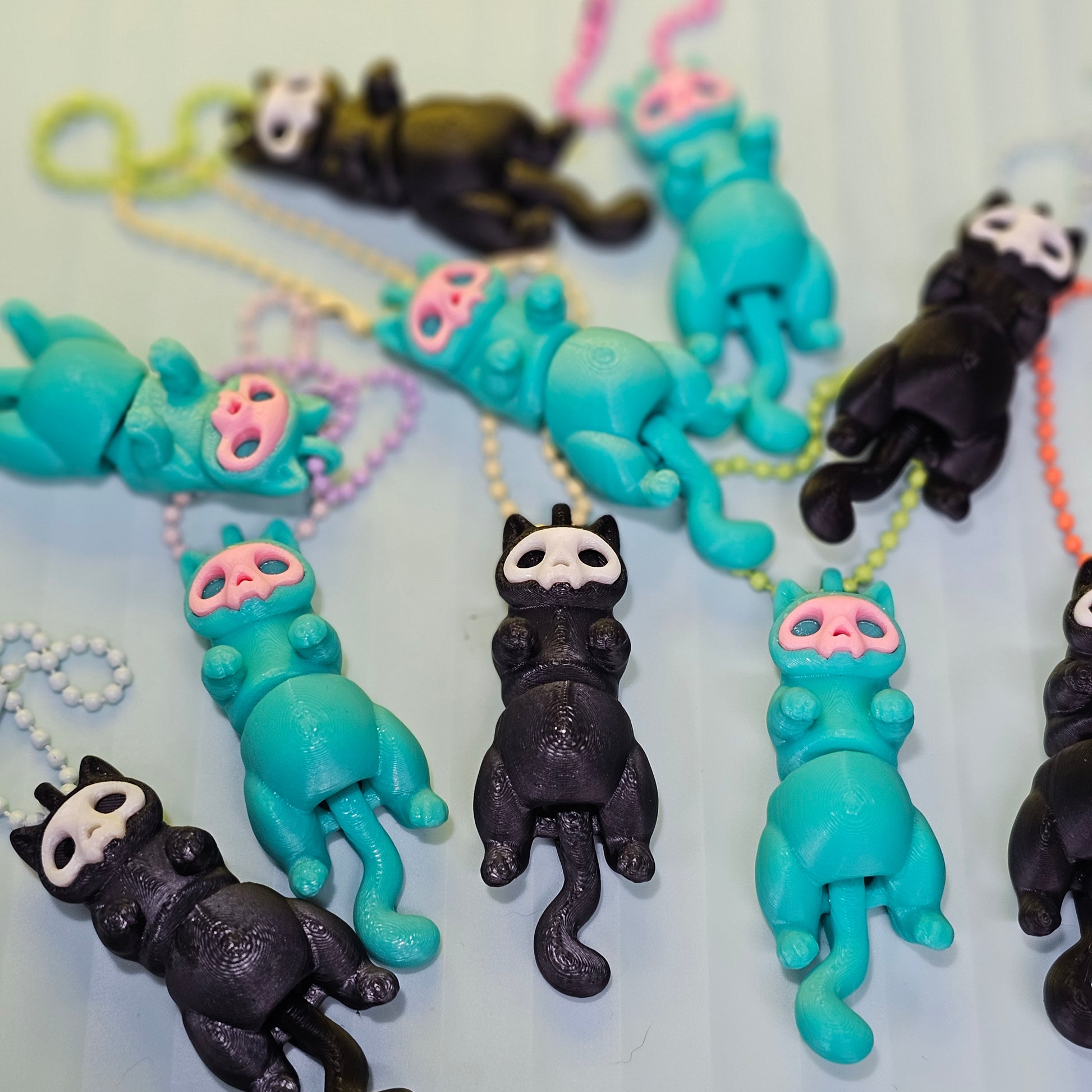 cats with skull faces one black and one teal. keychains. 
