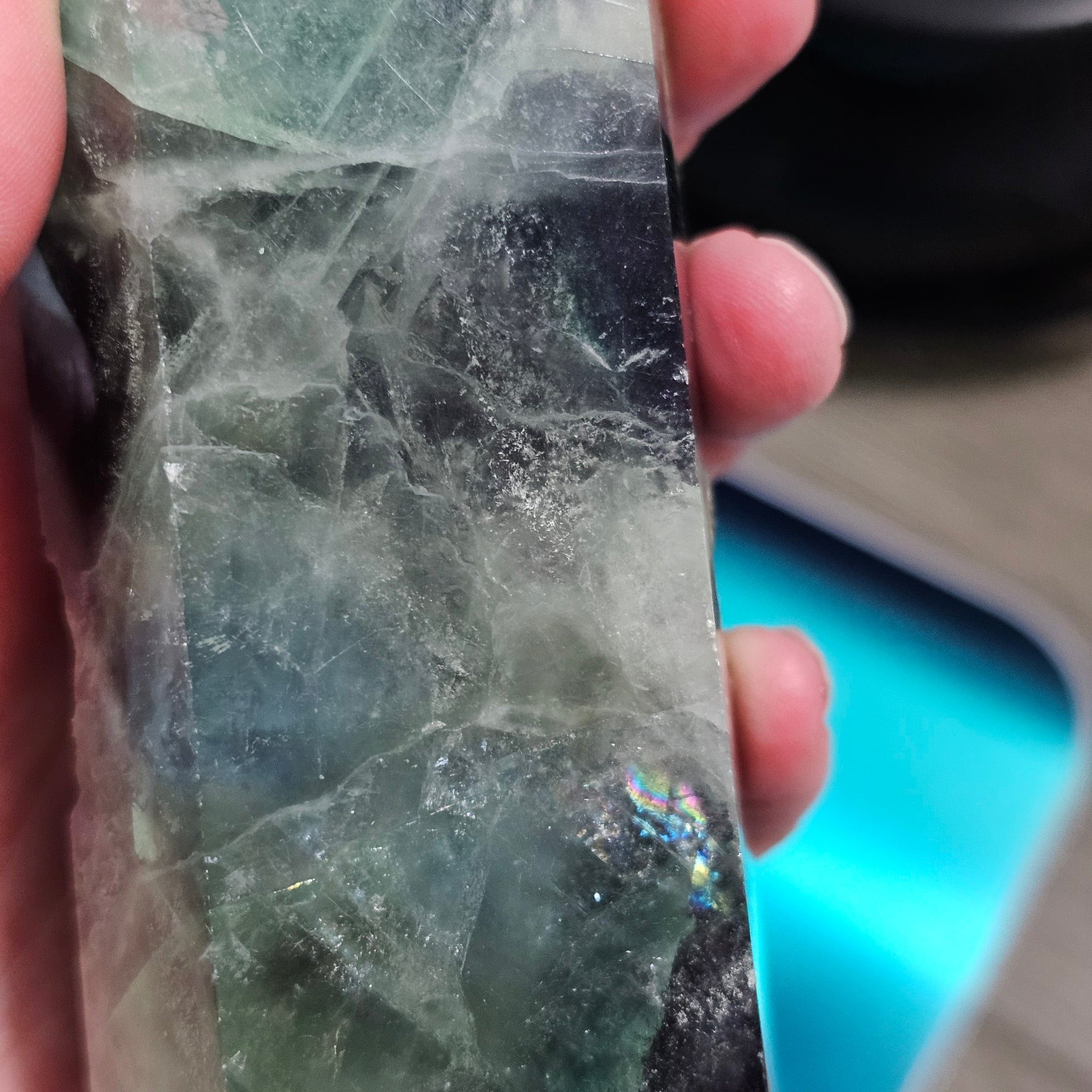 Close-up of a crystal held between fingers with a blurred background